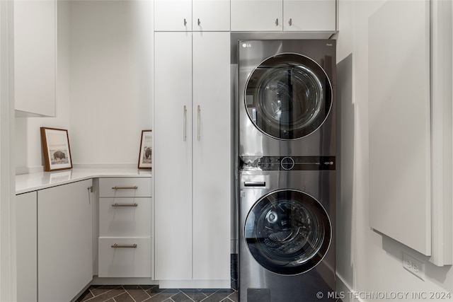 washroom featuring dark tile patterned flooring and stacked washing maching and dryer