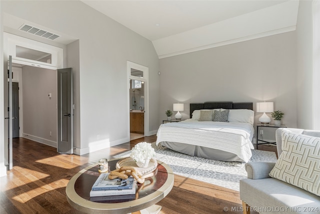 bedroom featuring dark hardwood / wood-style flooring, ensuite bath, and vaulted ceiling