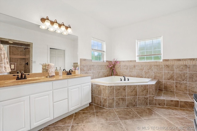 bathroom with independent shower and bath, a wealth of natural light, tile patterned floors, and vanity