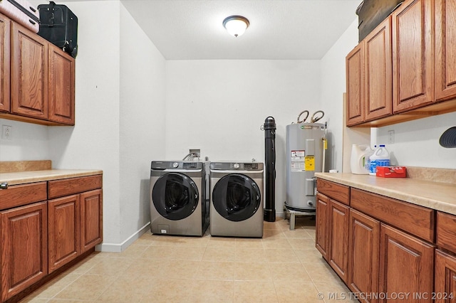 clothes washing area featuring water heater, cabinets, and washing machine and clothes dryer