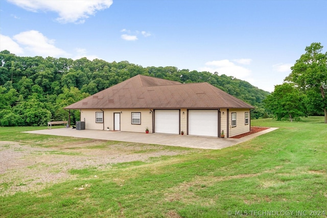 exterior space with a garage, a front lawn, and central AC