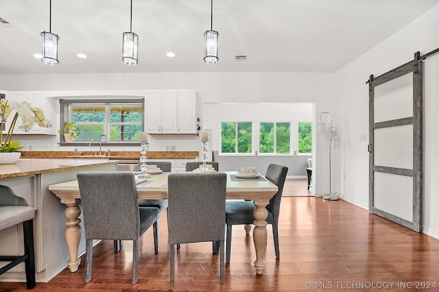 dining area featuring a barn door, wood-type flooring, plenty of natural light, and sink