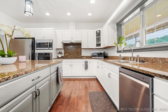 kitchen with appliances with stainless steel finishes, white cabinets, hanging light fixtures, and sink