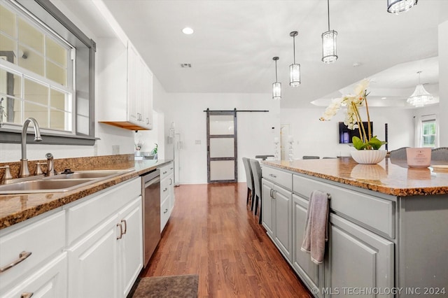 kitchen featuring stainless steel dishwasher, a barn door, white cabinets, and sink