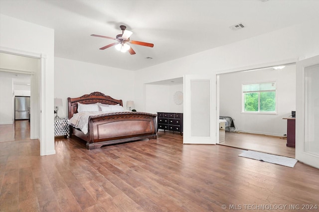 bedroom with ceiling fan, wood-type flooring, and stainless steel refrigerator