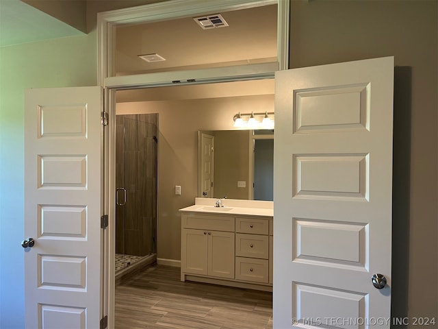 bathroom with a shower with shower door, vanity, and wood-type flooring