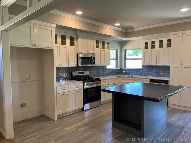 kitchen with white cabinets, a center island, appliances with stainless steel finishes, decorative backsplash, and sink