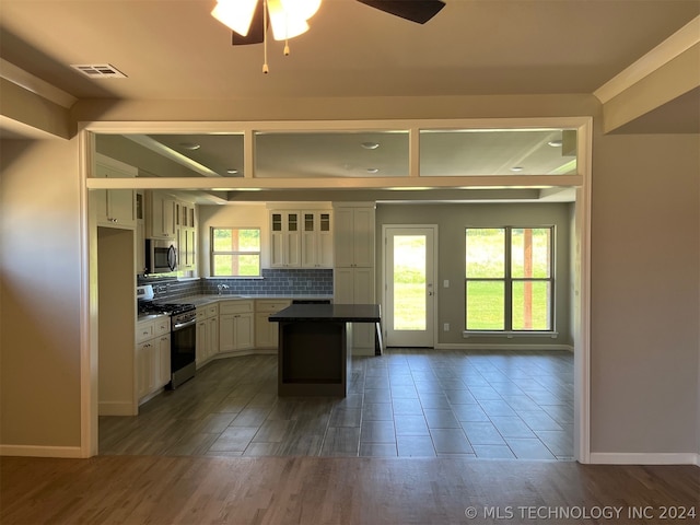 kitchen featuring decorative backsplash, range with gas stovetop, ceiling fan, and white cabinets