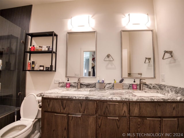 full bathroom featuring toilet, double vanity, walk in shower, and a sink