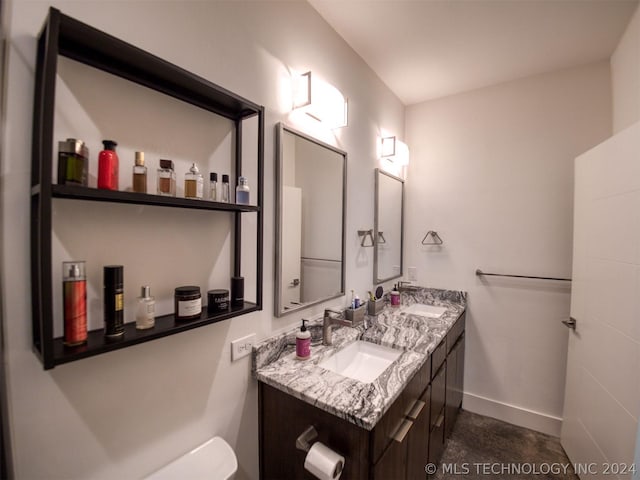 full bathroom featuring double vanity, a sink, toilet, and baseboards