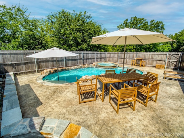 view of pool with a fenced backyard, a pool with connected hot tub, and a patio