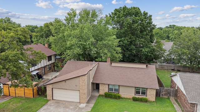 view of front of property with brick siding, fence, concrete driveway, a front yard, and a garage