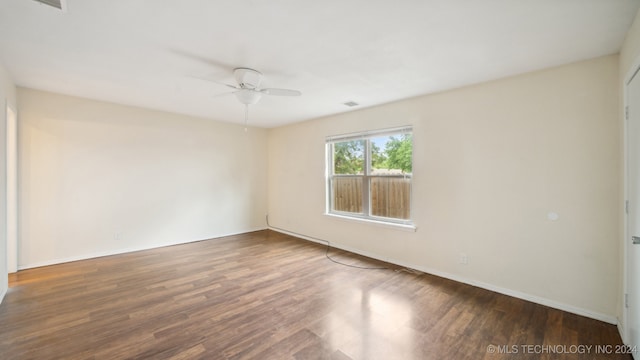 empty room with ceiling fan, visible vents, baseboards, and wood finished floors