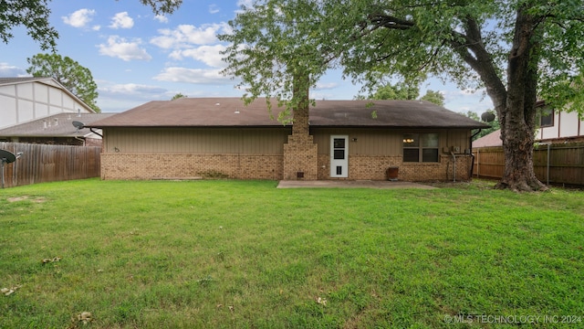 rear view of property with a yard, brick siding, a fenced backyard, and a patio area