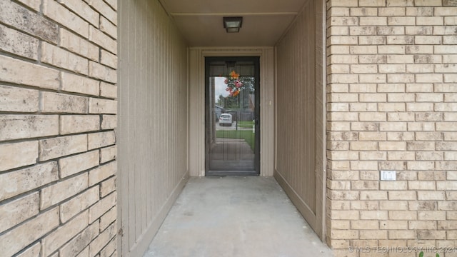 property entrance featuring brick siding and a shingled roof