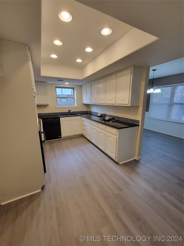 kitchen featuring wood finished floors, a sink, white cabinets, black dishwasher, and a raised ceiling