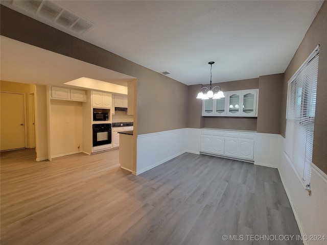 unfurnished dining area with baseboards, light wood-style floors, visible vents, and a chandelier