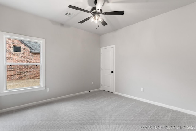 carpeted spare room featuring baseboards, visible vents, and ceiling fan