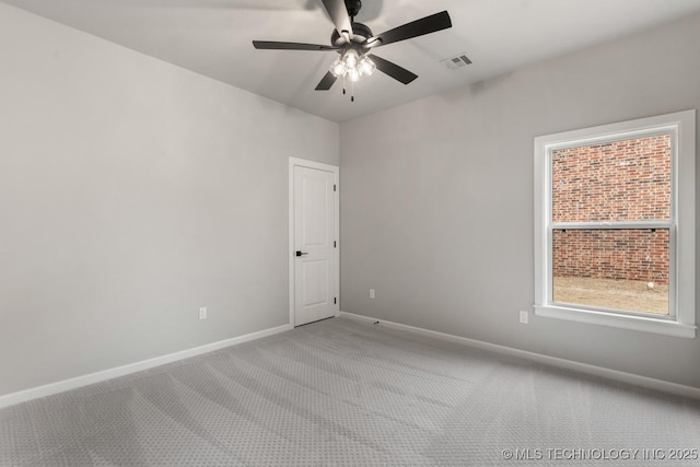 carpeted spare room with visible vents, baseboards, and ceiling fan