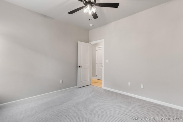 spare room with ceiling fan, baseboards, and light colored carpet