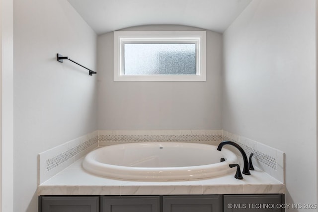 bathroom with vaulted ceiling and a bath