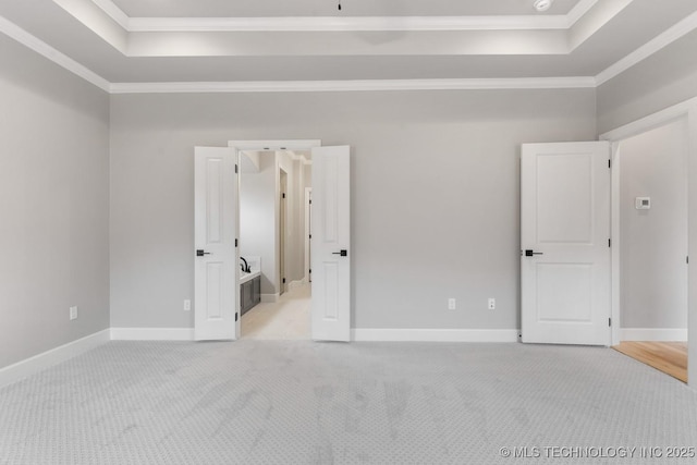 unfurnished bedroom featuring a tray ceiling, light colored carpet, and crown molding