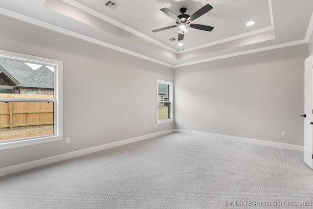 spare room with baseboards, visible vents, a raised ceiling, and crown molding