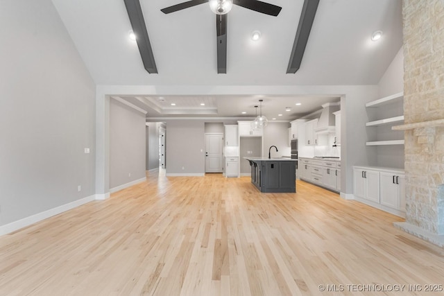 unfurnished living room featuring recessed lighting, light wood-style floors, a sink, ceiling fan, and baseboards