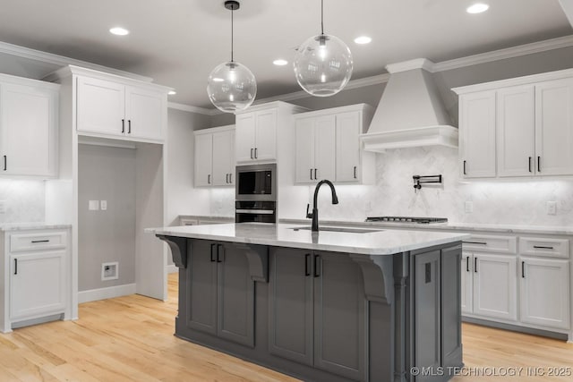 kitchen with a sink, ornamental molding, custom exhaust hood, and white cabinetry