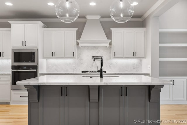 kitchen featuring crown molding, stainless steel appliances, custom range hood, white cabinets, and a sink