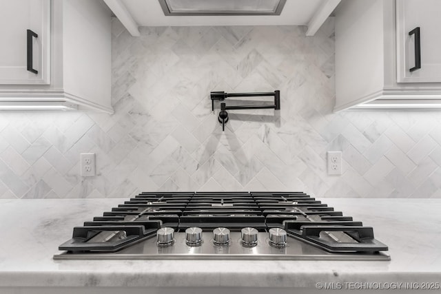 details featuring white cabinets, stainless steel gas cooktop, decorative backsplash, and light stone countertops