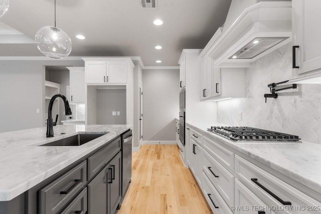 kitchen with visible vents, custom range hood, white cabinetry, and a sink