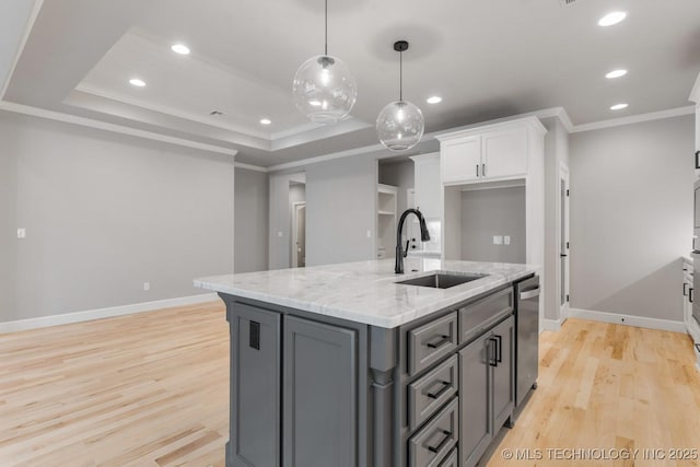 kitchen featuring a raised ceiling, light wood-style floors, white cabinetry, a sink, and dishwasher