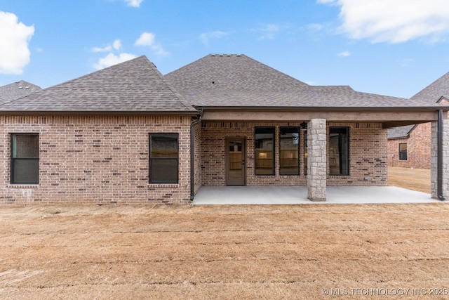 back of property featuring a patio, brick siding, and roof with shingles