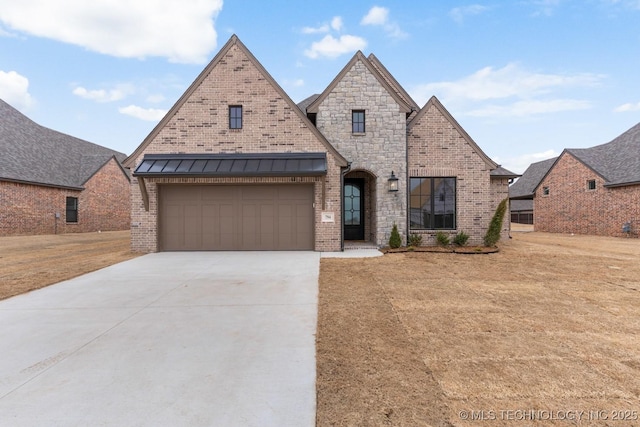 french country home with a garage, driveway, and brick siding