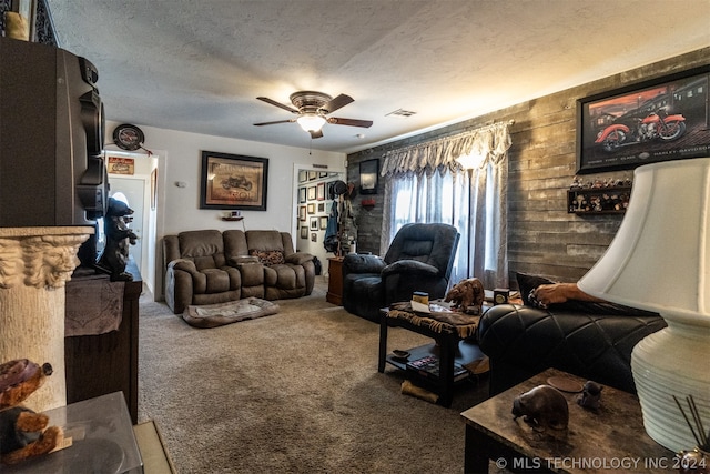 carpeted living room with a textured ceiling, ceiling fan, and wooden walls