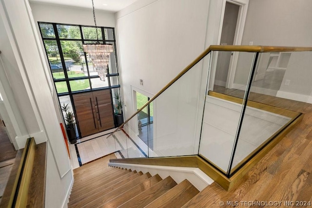 stairs featuring hardwood / wood-style floors and a notable chandelier