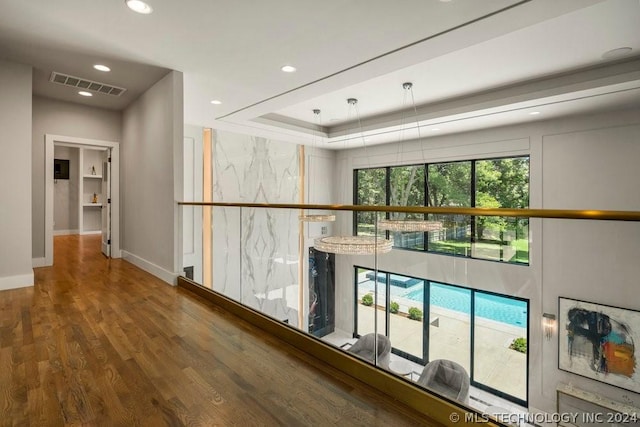 hallway with hardwood / wood-style floors and a raised ceiling