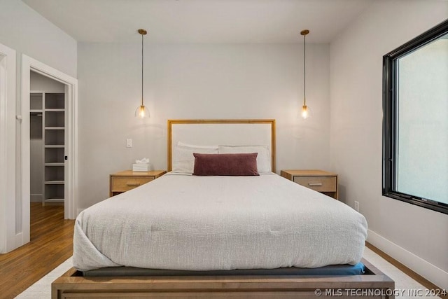 bedroom with wood-type flooring and a walk in closet