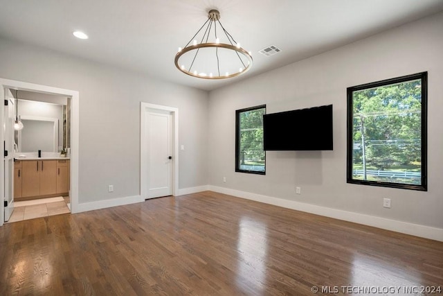 interior space with hardwood / wood-style flooring, a chandelier, ensuite bathroom, and multiple windows