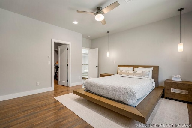 bedroom with ceiling fan, ensuite bathroom, a spacious closet, and hardwood / wood-style floors