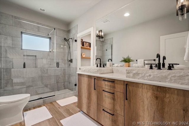 bathroom featuring a shower with door, toilet, and vanity