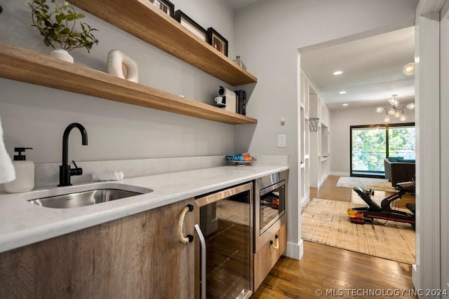 bar featuring sink, stainless steel microwave, dark hardwood / wood-style floors, and beverage cooler