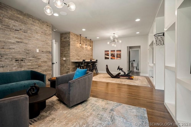 living room with hardwood / wood-style floors, a chandelier, and brick wall