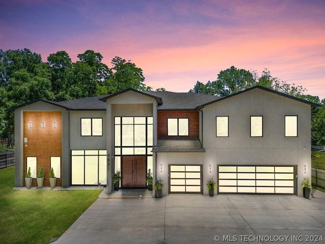 contemporary home featuring a garage and a lawn