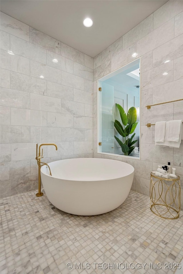 bathroom with a tub and tile walls