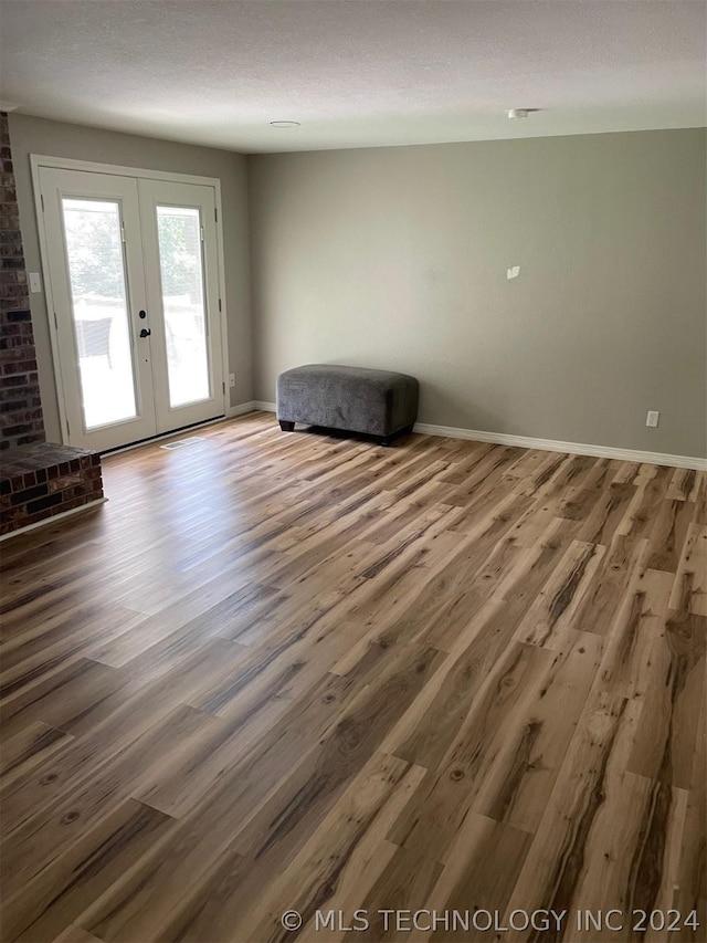 spare room with wood-type flooring, french doors, and a textured ceiling