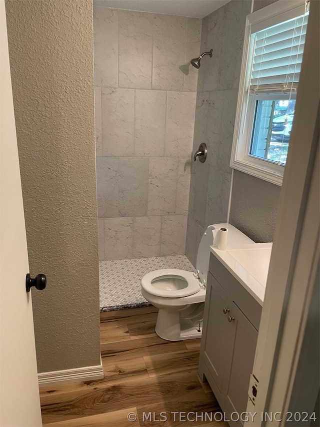 bathroom featuring vanity, toilet, hardwood / wood-style floors, and a tile shower