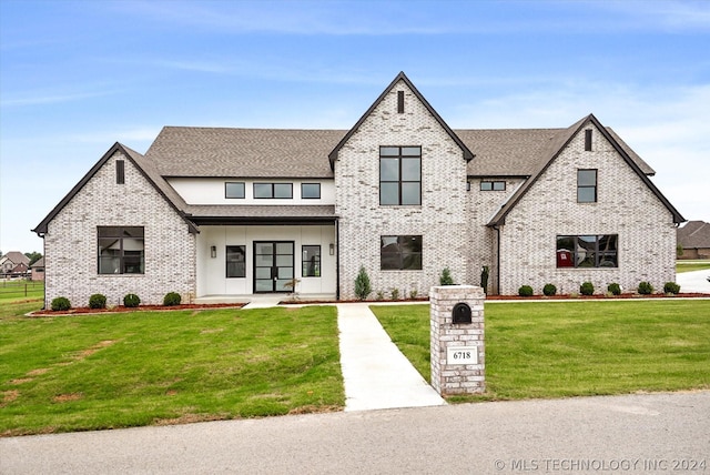 view of front of house featuring a front yard, brick siding, and roof with shingles