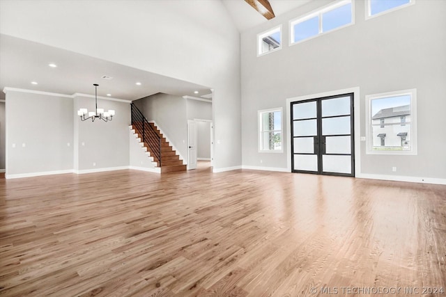 unfurnished living room with a high ceiling, light wood-type flooring, a notable chandelier, and beamed ceiling